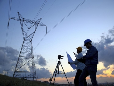 zwei Ingenieure arbeiten bei Sonnenuntergang vor einem Elektrizitätswerk